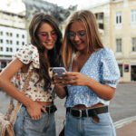 Dvije djevojke koriste pametni telefon i uspoređuju mogućnosti mobitela