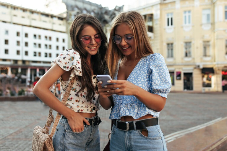 Dvije djevojke koriste pametni telefon i uspoređuju mogućnosti mobitela